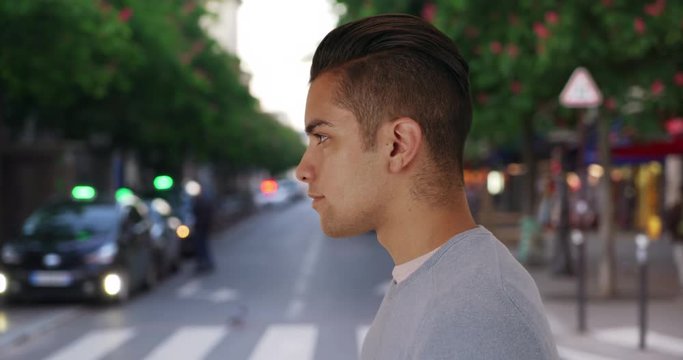Profile of Latino male with cool undercut standing on city street