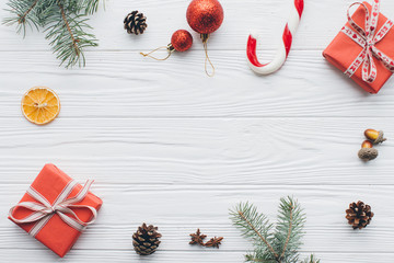 Christmas composition. Gifts, pine cones, fir branches, candy, spices and other decorations on wooden white background. Flat lay, top view.