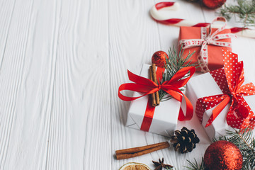 Christmas composition. Gifts, pine cones, fir branches, candy, spices and other decorations on wooden white background. Flat lay, top view.