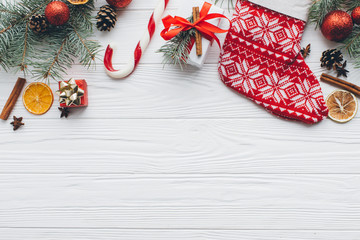 Christmas composition. Gifts, pine cones, fir branches, candy, spices and other decorations on wooden white background. Flat lay, top view.