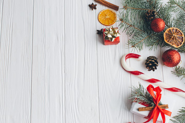 Christmas composition. Gifts, pine cones, fir branches, candy, spices and other decorations on wooden white background. Flat lay, top view.