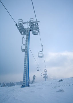 Mountain ski lift frozen and covered with frost and ice on sky background