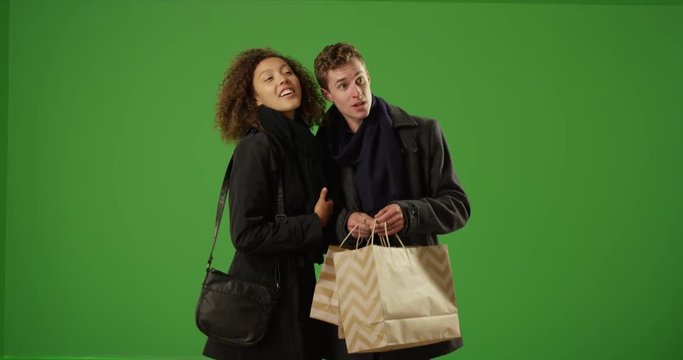 Happy couple standing outdoors and looking into shopping bags on green screen. On green screen to be keyed or composited. 