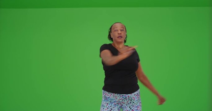 An older black woman doing aerobics in the gym on green screen. On green screen to be keyed or composited. 