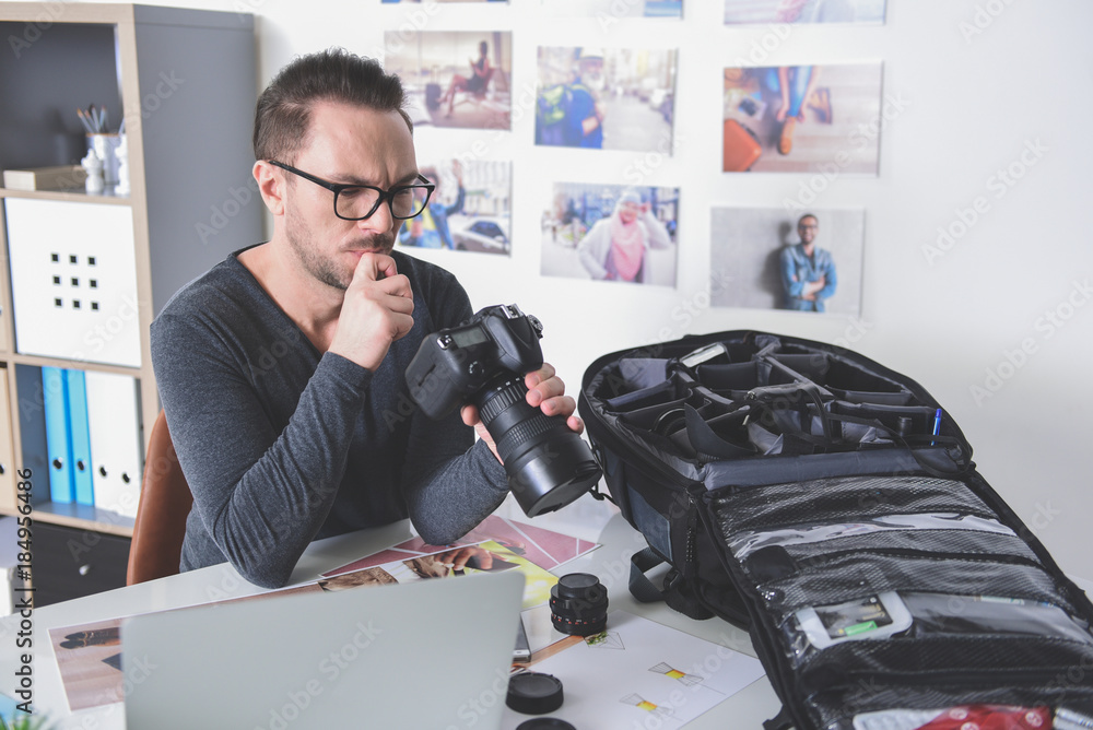 Poster portrait of pensive bearded man looking at screen of digital device for creating photos. he situatin