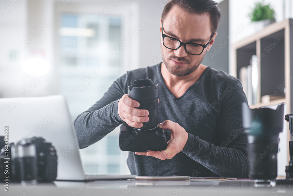 Poster portrait of serene bearded male having job with digital device for creating photos while locating at