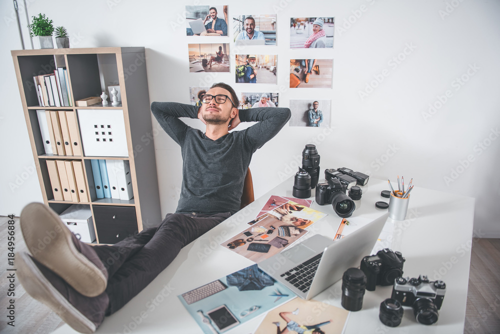 Poster top view full length of outgoing bearded young man resting at work in modern office. different image
