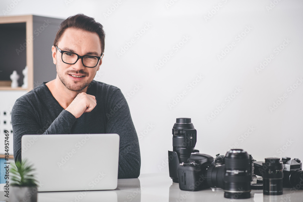 Poster portrait of smiling bearded man having work at digital device while locating at table. labor concept