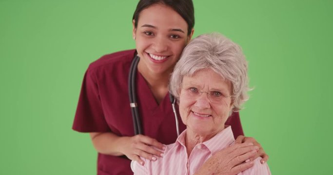 Female nurse or caregiver with elderly patient smiling for portrait on greenscreen . Hispanic woman care taker medical health care professional and senior on green screen for compositing. 4k
