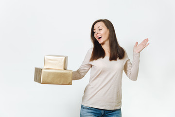 Pretty caucasian fun young happy woman in light clothes with shy charming smile, brown hair and two golden gift boxes with present, celebrating holiday on white background isolated for advertisement.