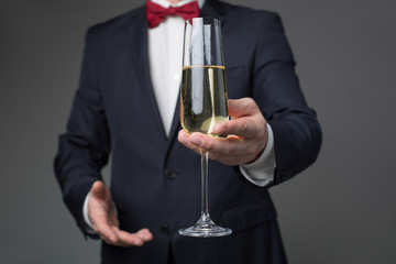 Close up of gentleman arm proposing to drink alcohol beverage with him. Focus on glass of sparkling champagne. Isolated