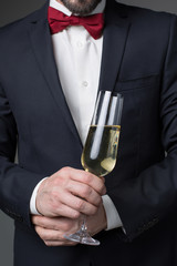 Close up of male hand holding glass of champagne. Man is standing in elegant suit