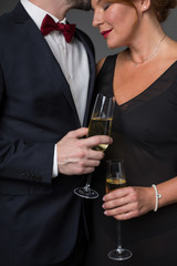 Low angle of loving couple celebrating their anniversary with champagne. Man is kissing female forehead with gentleness. Focus on glasses in their hands