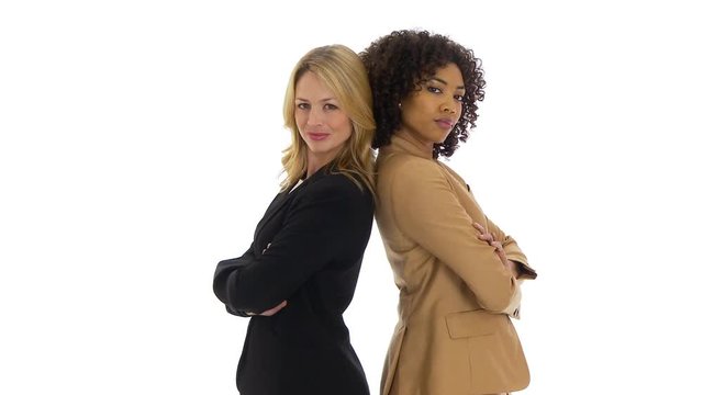 Two businesswomen standing back to back looking at camera