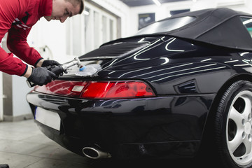 Naklejka premium Car detailing - Worker with orbital polisher in auto repair shop. 