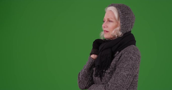 Caucasian woman reacting to something she's watching off camera on greenscreen. Woman in scarf and sweater looking at something off camera with concern on green screen to be keyed or composited. 