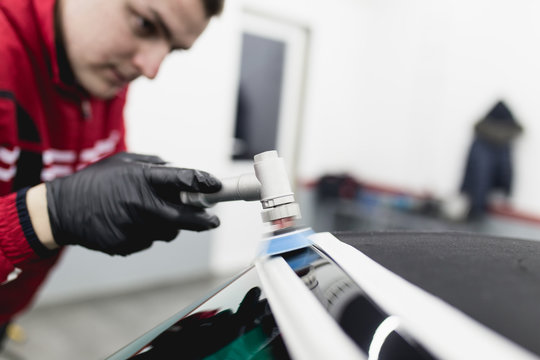 Car detailing - Worker with orbital polisher in auto repair shop. 