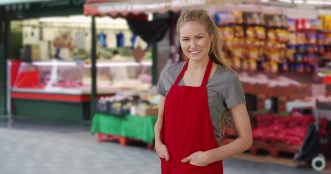 Female Caucasian grocer standing happily at outdoor market