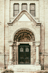 Fototapeta na wymiar Big double wooden door at Synagogue with arch, stairs and brick wall in Novi Sad, Serbia