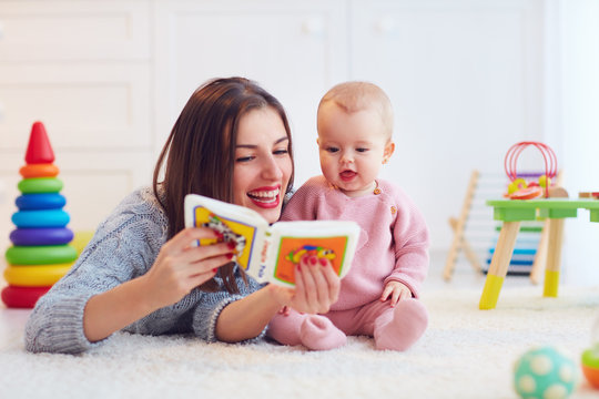 cute mother and daughter playing together, reading first book