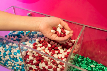 Woman hand holding group of red and white capsule medicines