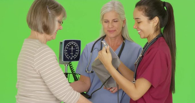 RN training nursing student to check patient blood pressure on green screen. On green screen to be keyed or composited. 