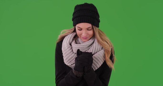Attractive millennial girl wearing beanie, scarf, and gloves on green screen. On green screen to be keyed or composited.