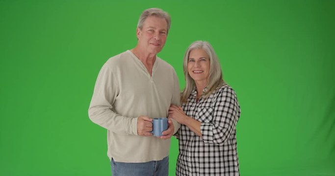 Lovely senior couple smiling at camera on green screen