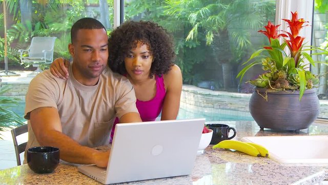 Couple using computer at kitchen counter