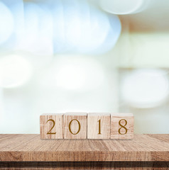 2018 new year greeting card, wooden cubes with 2018 on wood table over blur bokeh background with copy space for text, new year template