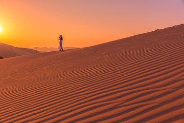 Woman walk alone on The red sand dunes in MUI NE, Vietnam is popular travel destination with long coastline, silver sand and huge sea waves.