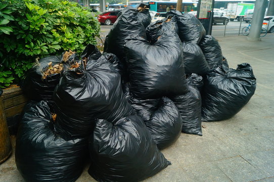 Black plastic bags filled with garbage, heaps of heaps, on the city sidewalk