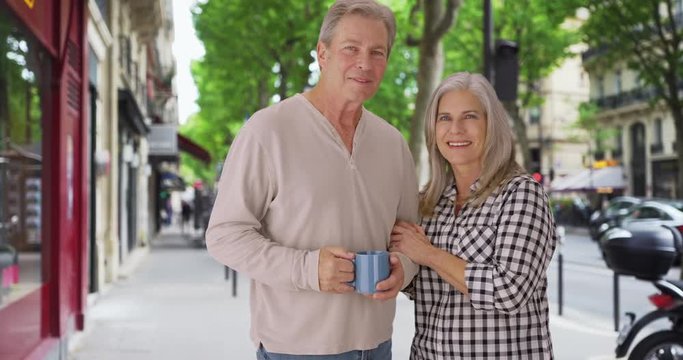 Loving old white couple stands happily on a London sidewalk