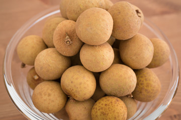 Bowl filled with an heap Dimocarpus Longan fruit on wooden background