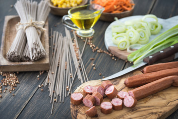 Slicing sousages for soba noodles cooking with leek, corn and korean carrot