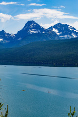 Two Kayaks paddle on a calm, quiet Lake McDonald in Glacier on a clear day