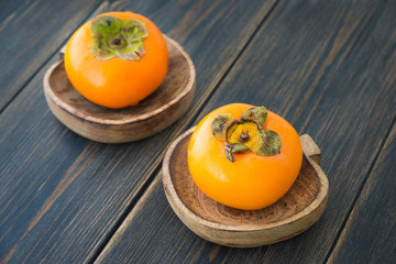 Fresh ripe solid persimmons in wooden plates