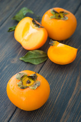 Sliced ripe persimmons with green leaves