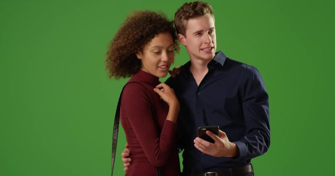 Young romantic couple using smartphone gps for directions on green screen. On green screen to be keyed or composited. 