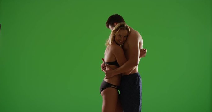Two millennials in love hugging at the beach during the sunset on green screen. On green screen to be keyed or composited. 