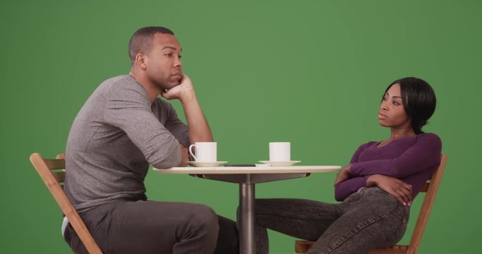 Black couple at outdoor caf_ at night having an argument on green screen. On green screen to be keyed or composited. 