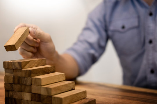 Business man hand put wooden blocks arranging stacking for development as step stair, Concept of growth and success plan