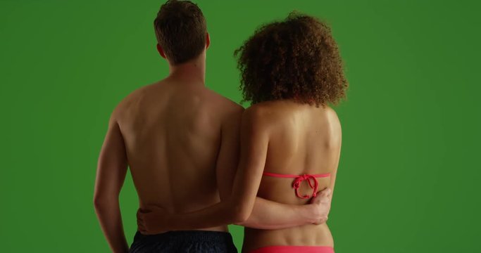 Attractive young couple holding each other on beach on green screen. On green screen to be keyed or composited. 