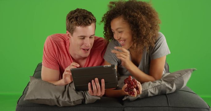 Couple of multiracial friends using tablet handheld device on green screen. On green screen to be keyed or composited. 
