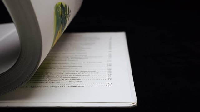 The hand turns over the pages of the book on black background. Closeup. Slow mo, slo mo, slow motion, high speed camera, 240fps, 250fps
