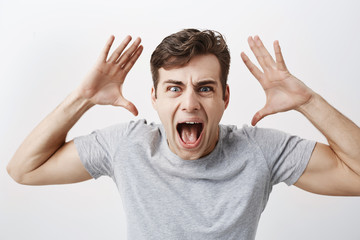 Excited male model dressed casually stares at camera with unbelievable gaze, screaming in surprise to recieve unexcpected news from relatives. People, facial expressions, emotions concept