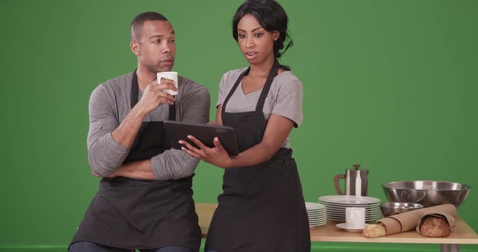 Restaurant workers having a meeting using tablet computer before opening on green screen. On green screen to be keyed or composited. 