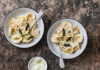 Pumpkin ravioli with sage butter and parmesan cheese on wooden background, top view. Delicious vegetarian, seasonal comfort food