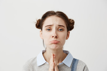 Portrait of girl 20s with upset look begging for mercy being disappointed with praying gestures....