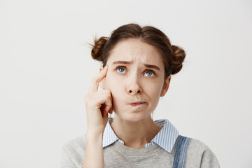 Headshot of adult girl looking up with frown expressing misunderstanding. Cute female student...